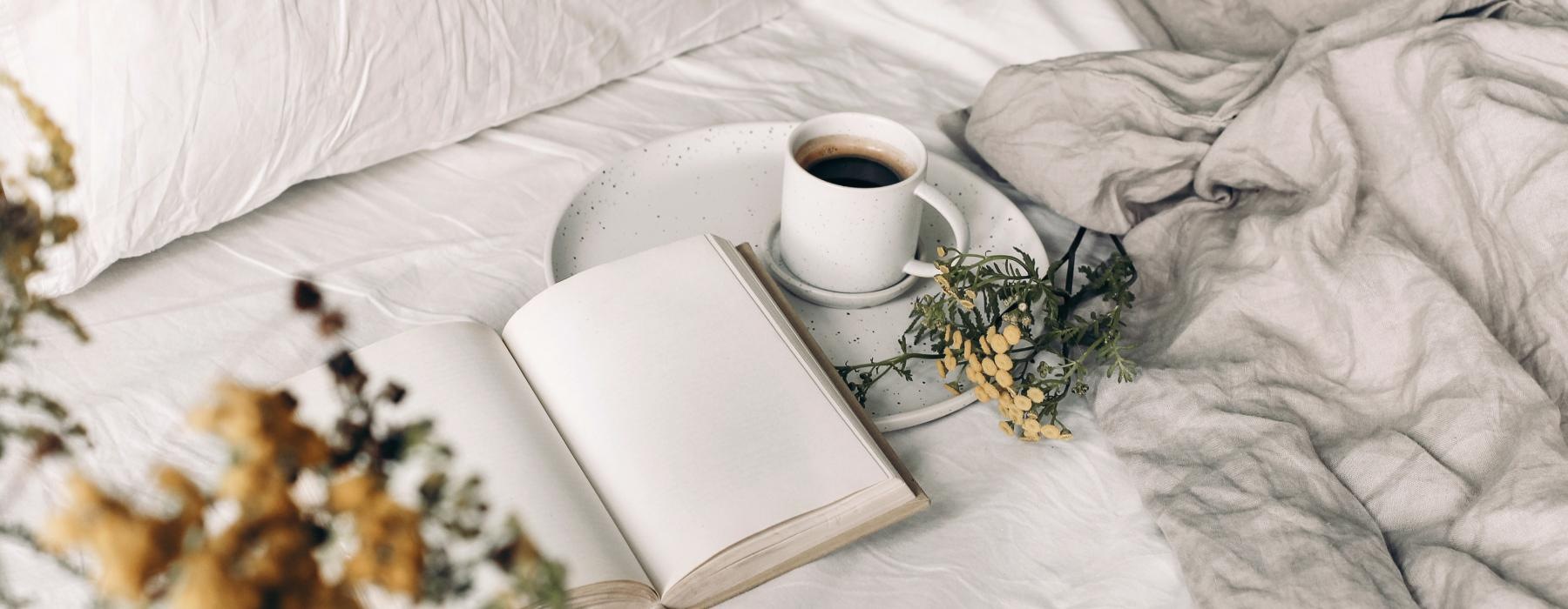 a laptop and a cup of coffee on a bed